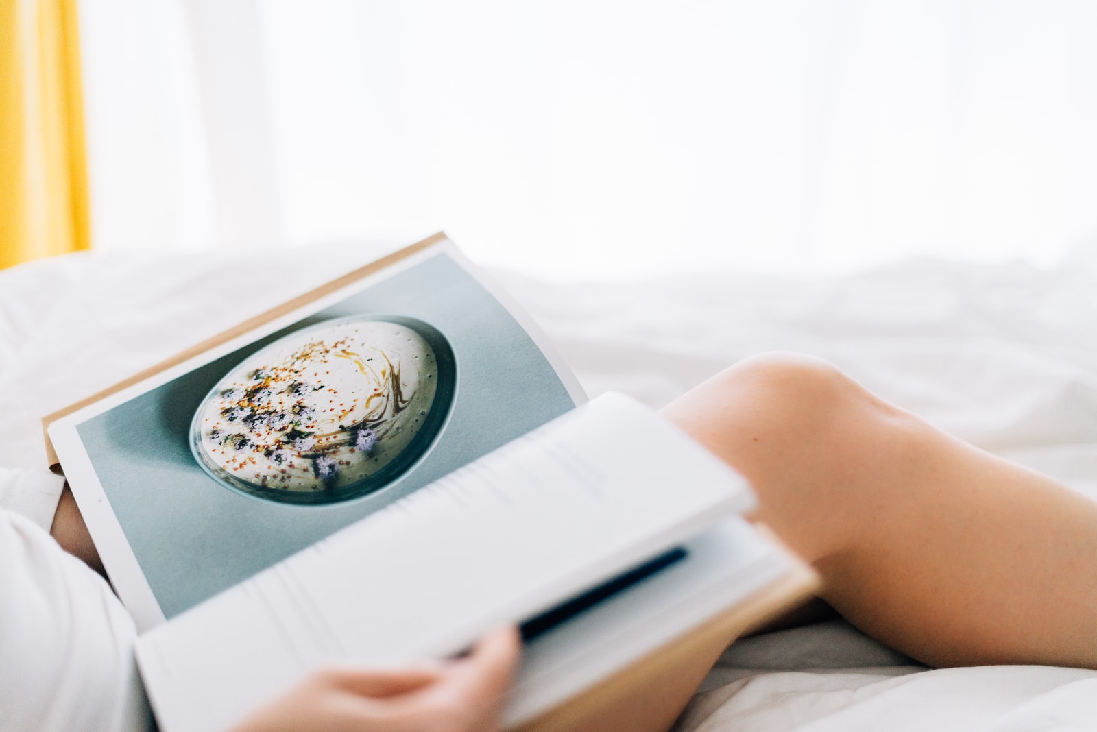 How to Create a Book of Custom Recipes person holding open magazine while laying on bed