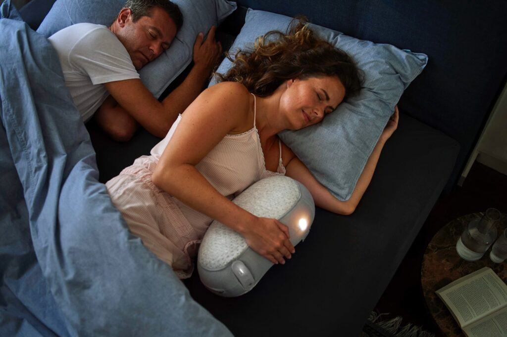 woman in white tank top lying on bed beside man in black shirt