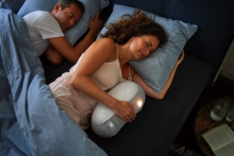 woman in white tank top lying on bed beside man in black shirt