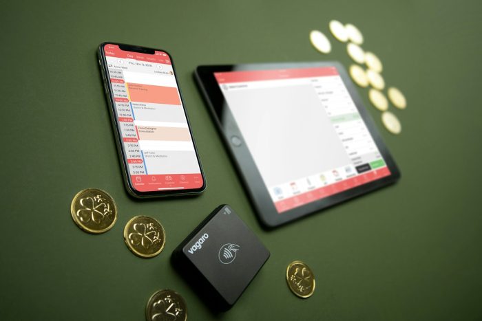 Smartphone, tablet, payment terminal, and coins on table